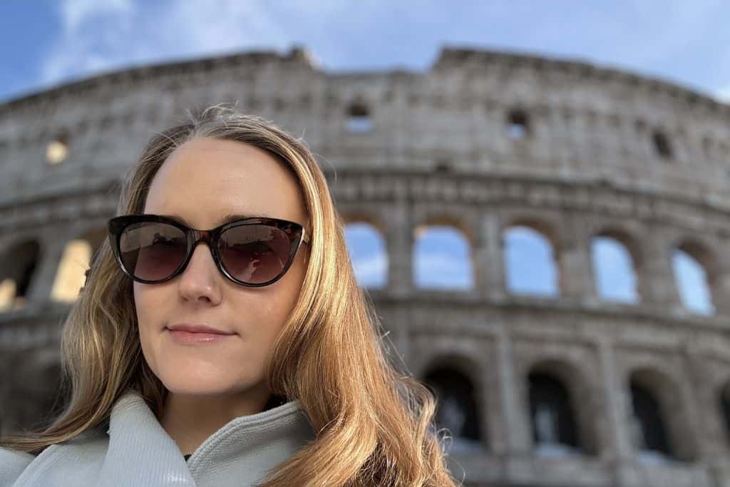 Blonde woman with sunglasses in front of Colosseum, gladiator arena