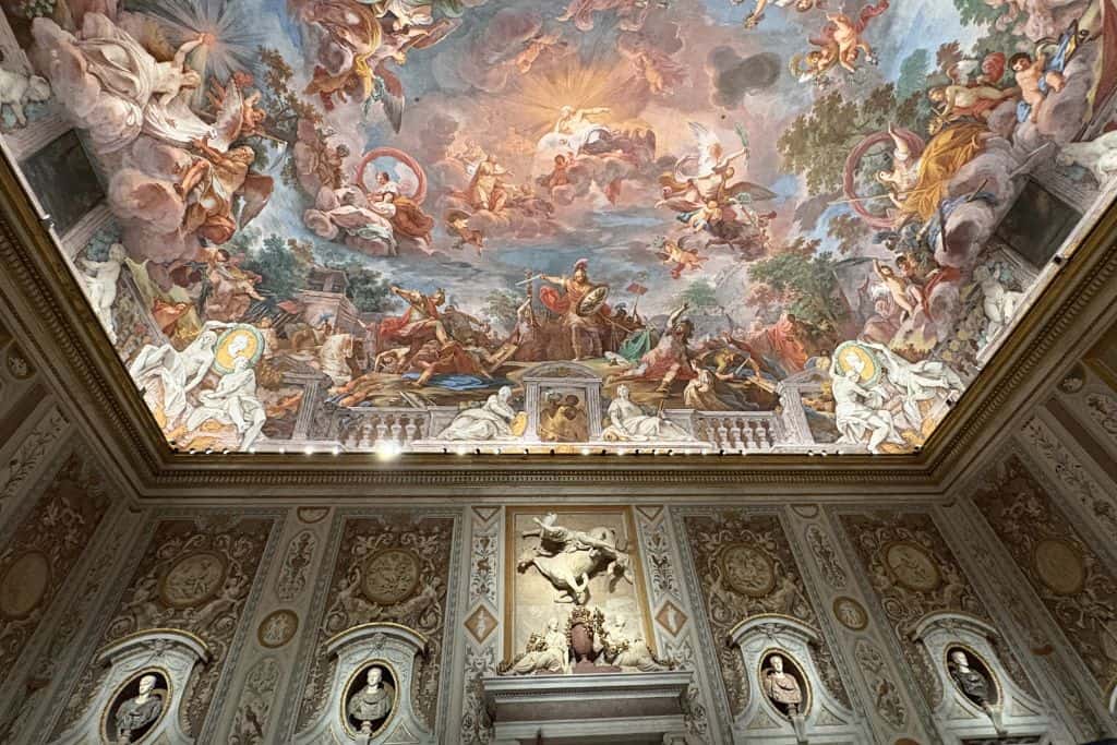 Image shows gorgeous pink, and soft colored ceiling surrounded by statues
